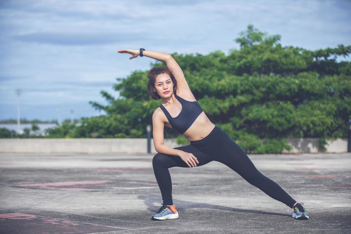 athletische frau asiatische aufwärmen und junge sportlerin sitzen auf einem training und stretching in einem park vor dem läufer im freien, gesundes lebensstilkonzept foto