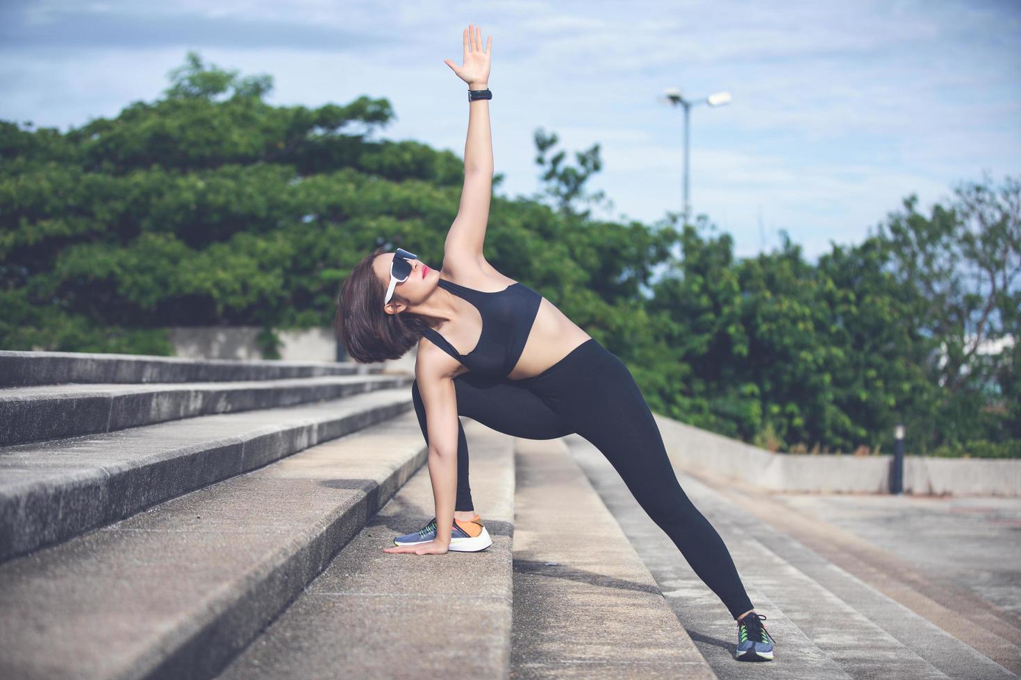 athletische frau asiatische aufwärmen und junge sportlerin sitzen auf einem training und stretching in einem park vor dem läufer im freien, gesundes lebensstilkonzept foto