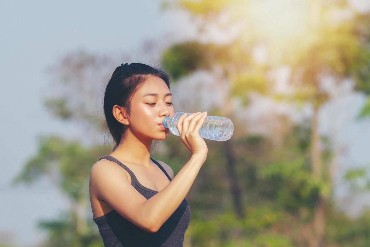 sportliche frau asiatisches trinkwasser im freien an einem sonnigen tag foto