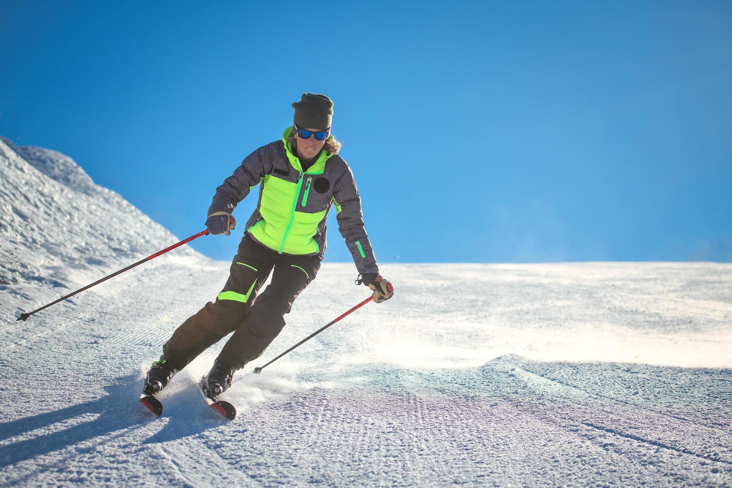 Skifahrer, der alpines Skifahren auf der Piste eines Skigebiets praktiziert foto