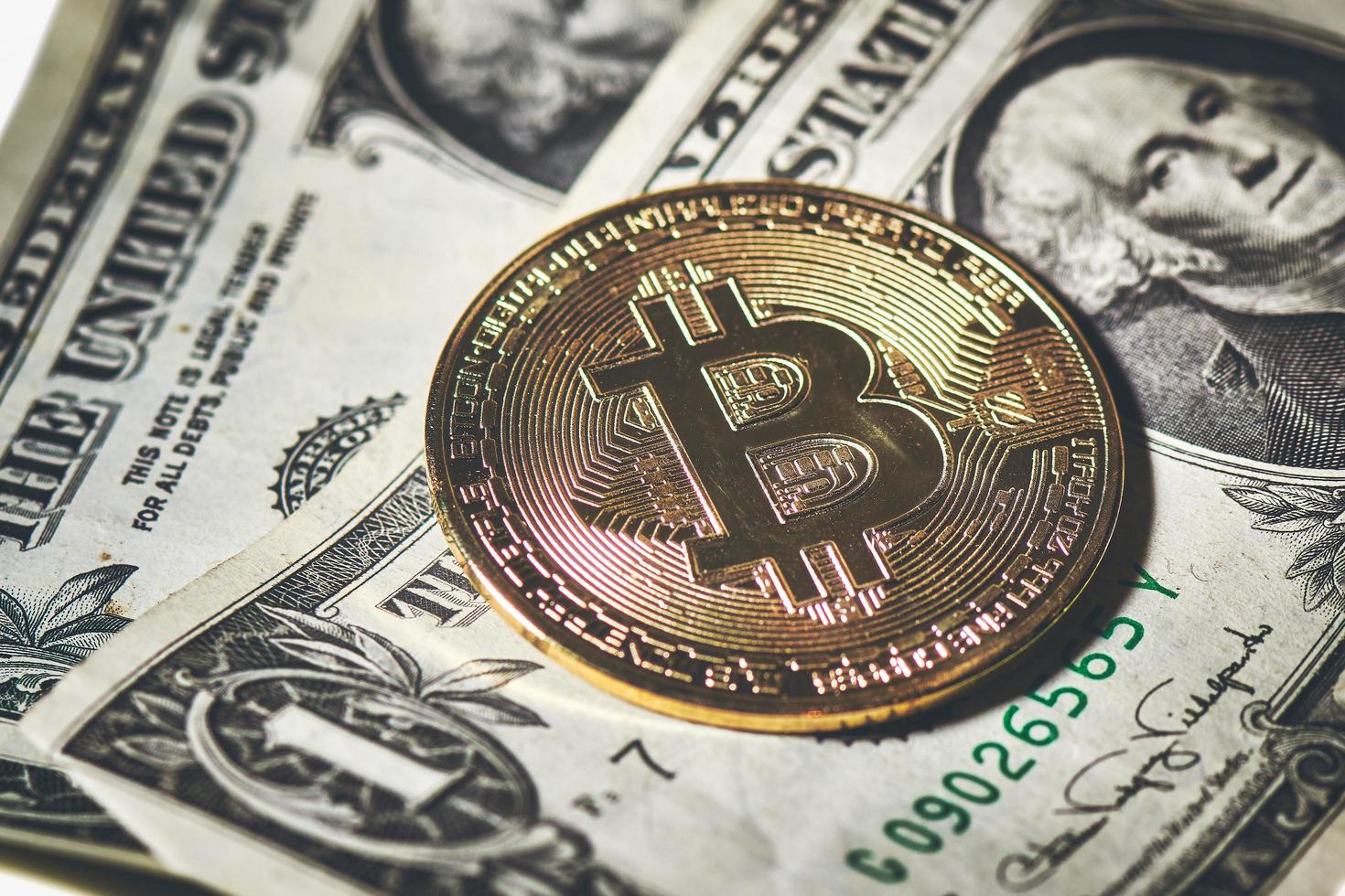 eine Bitcoin-Münze, die auf US-Papierdollar ruht foto