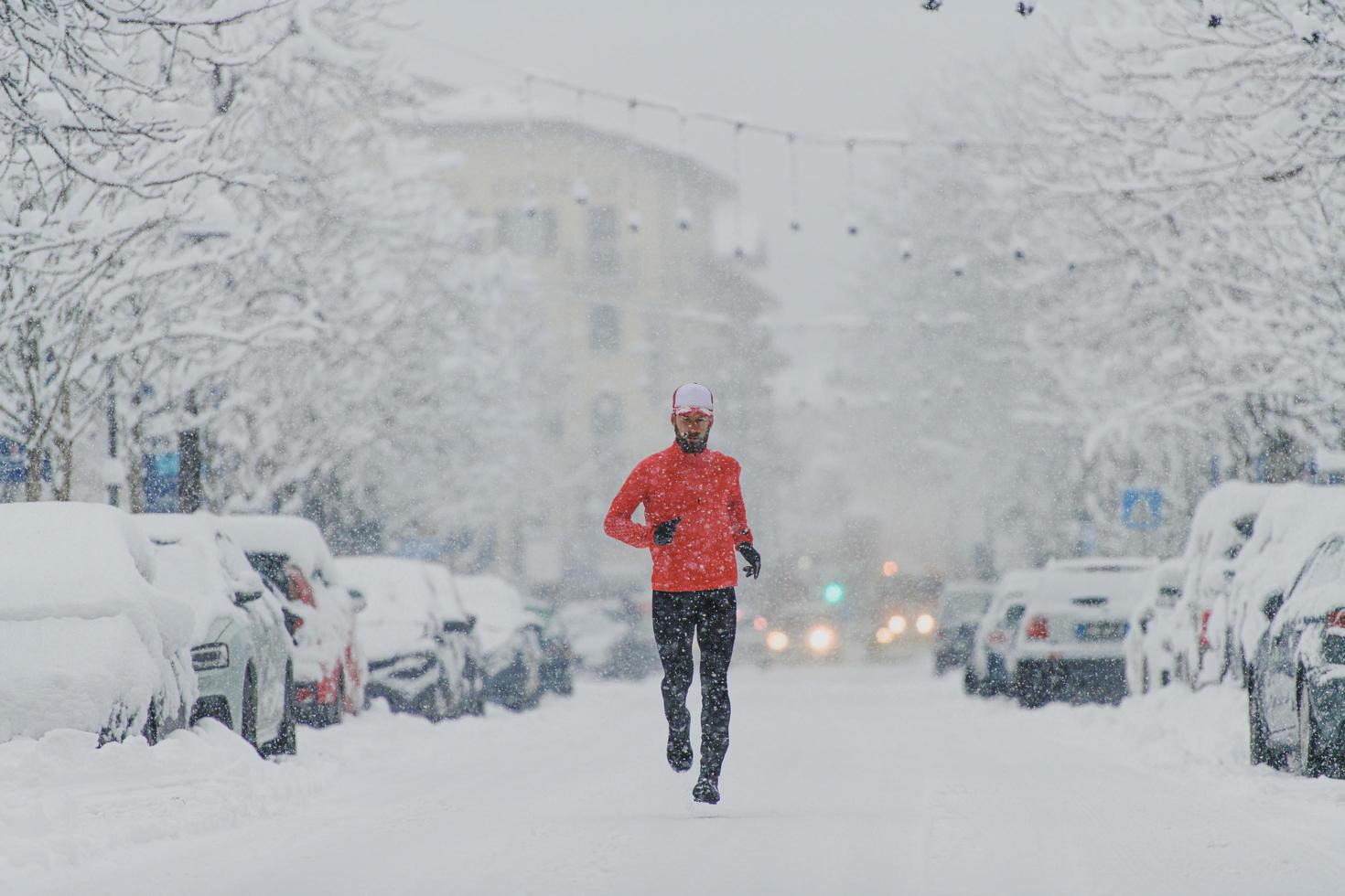 Junger Mann Läufer unter einem Schneefall in der Stadt foto