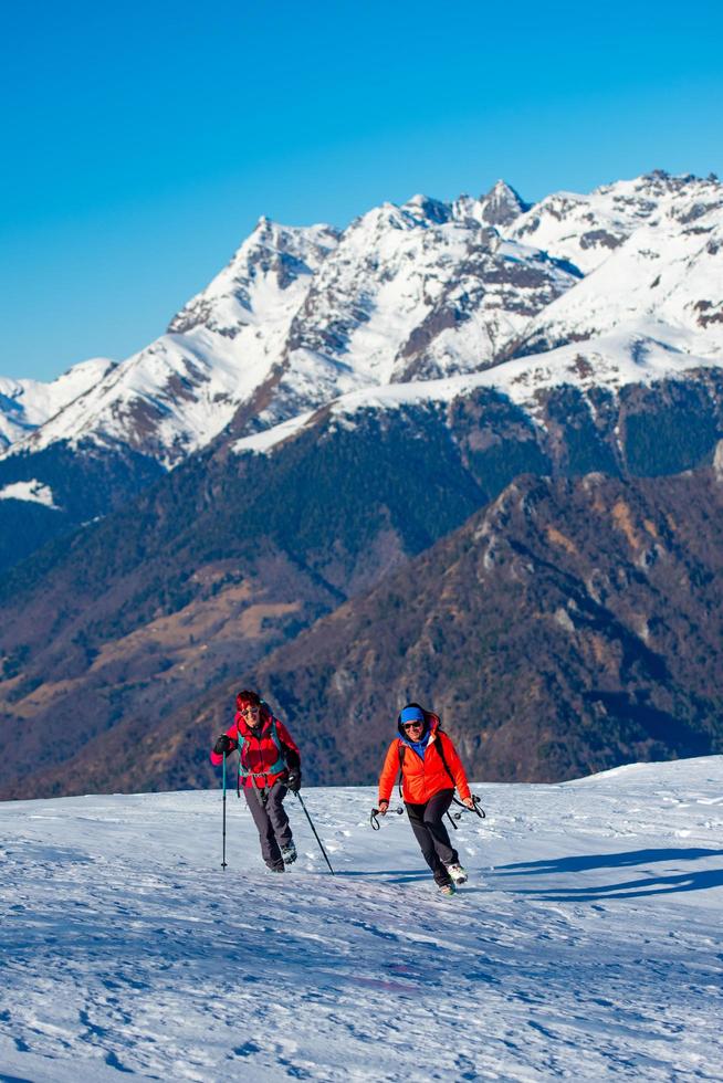 Zwei Freundinnen bei einem Bergsteigerspaziergang im Schnee foto