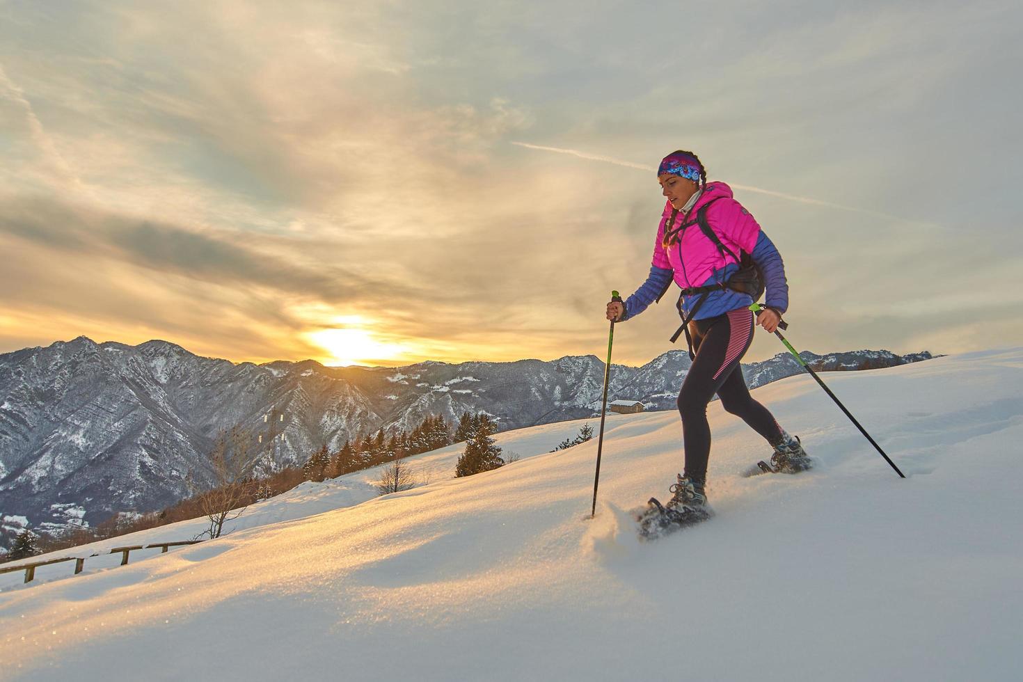 sportliches Mädchen mit Schneeschuhen in Sonnenuntergangslandschaft foto