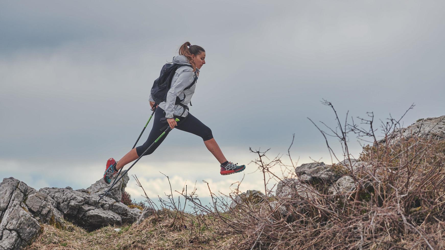 sportliches Mädchen springt während eines alpinen Trekkings zwischen den Steinen foto