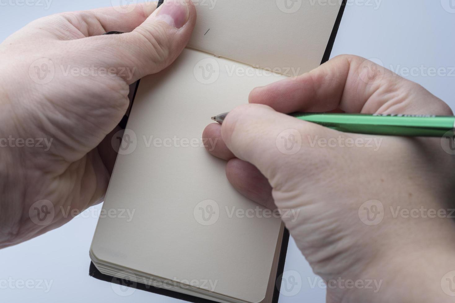 Hände eines Mannes, der ein Notizbuch und einen Stift auf einem weißen Hintergrund hält. foto