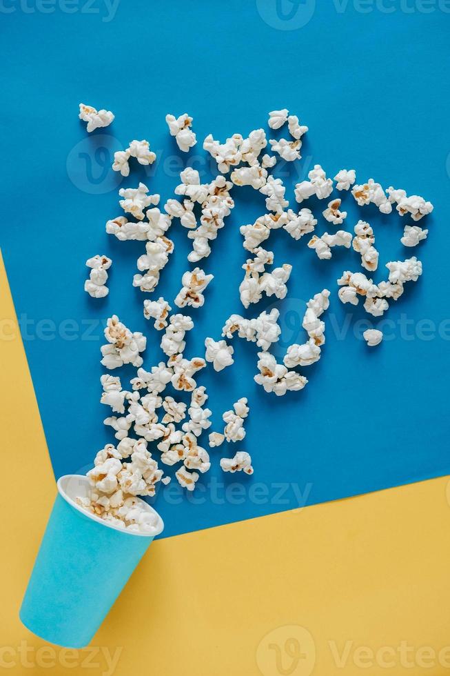 Popcorn in blauen Pappbechern auf gelbem und blauem Hintergrund. Ansicht von oben. kopieren, leerer platz für text foto