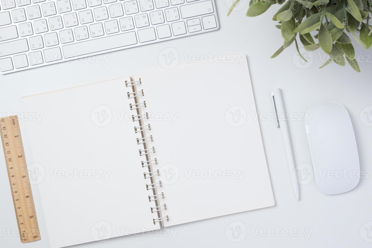 draufsicht arbeitstisch mit tastaturmaus und notizbuch auf weißem tischhintergrund foto