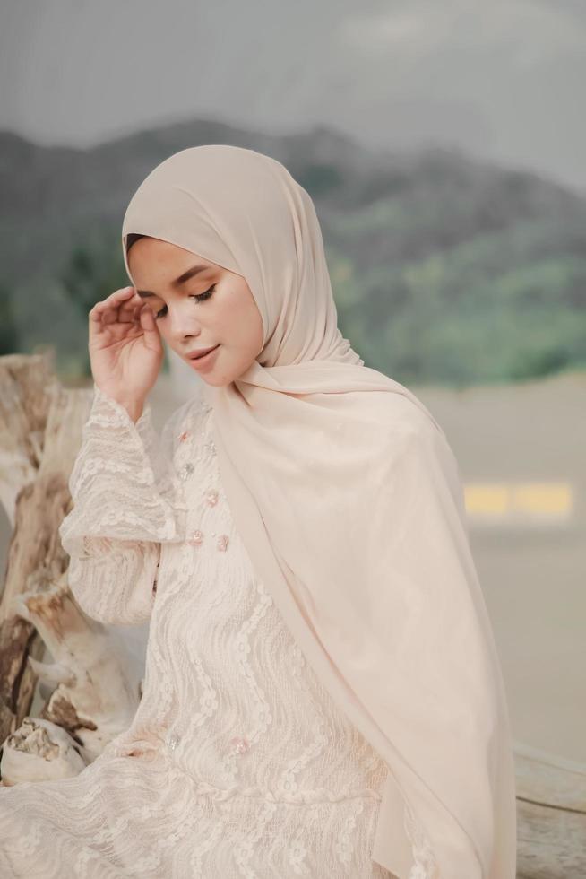 Schönes islamisches weibliches Modell in Hijab-Mode, ein modernes Hochzeitskleid für muslimische Frauen geht am Sand und am Meer entlang. ein asiatisches mädchenmodell, das hijab verwendet, das spaß am strand hat. Foto vor der Hochzeit