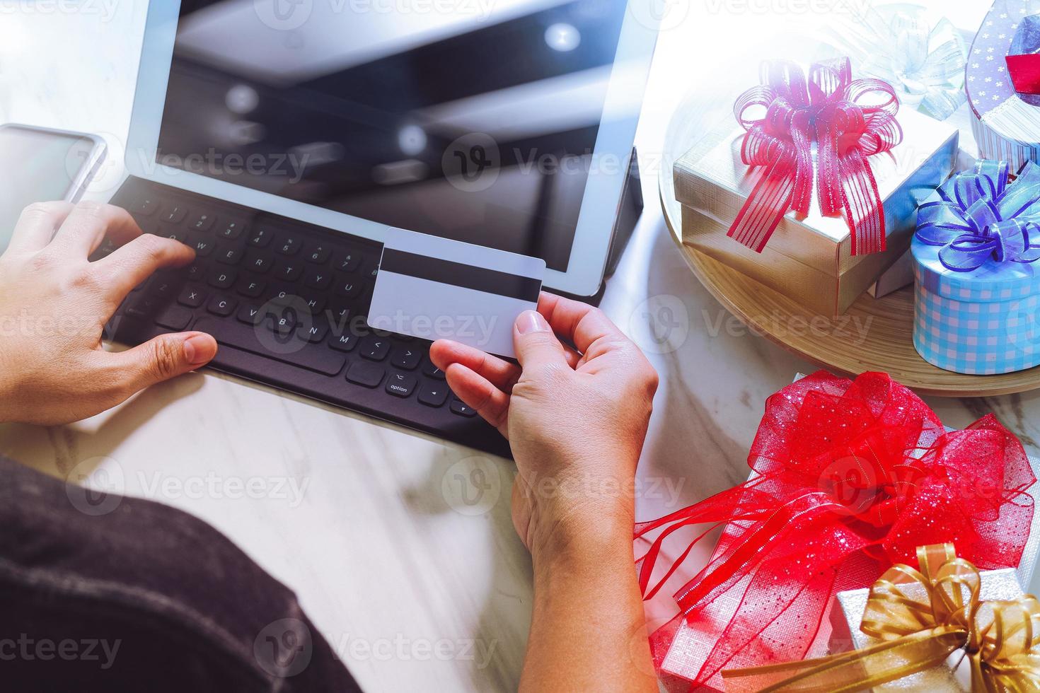 geschenk, das kreative hand mit kreditkarte und hand mit geschenk gibt. geschenklieferung, überraschung, tablet-computer, der intelligentes tastatur-smartphone auf mable-schreibtisch andockt, filterfilmeffekt foto