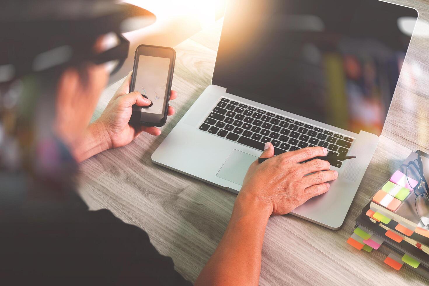 Designerhand, die an einer Videokonferenz mit Laptop und Smartphone am Schreibtisch im Büro teilnimmt foto