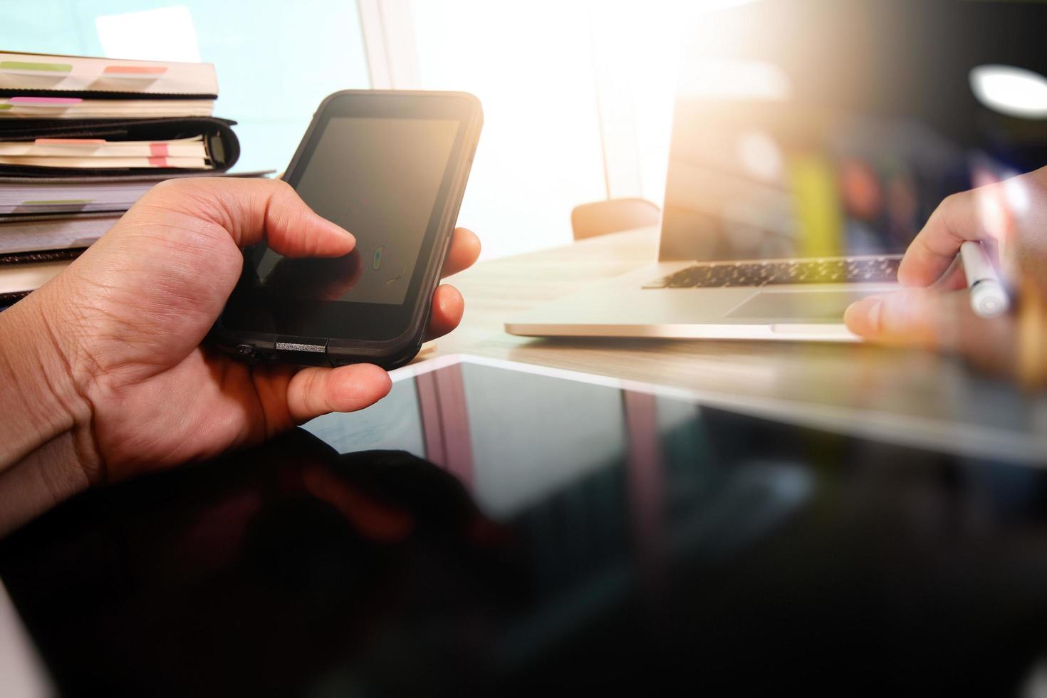 Designer-Hand, die mit digitalen Tablet- und Laptop-Computern und Buchstapeln und Augenglas auf Holzschreibtisch als Konzept arbeitet foto