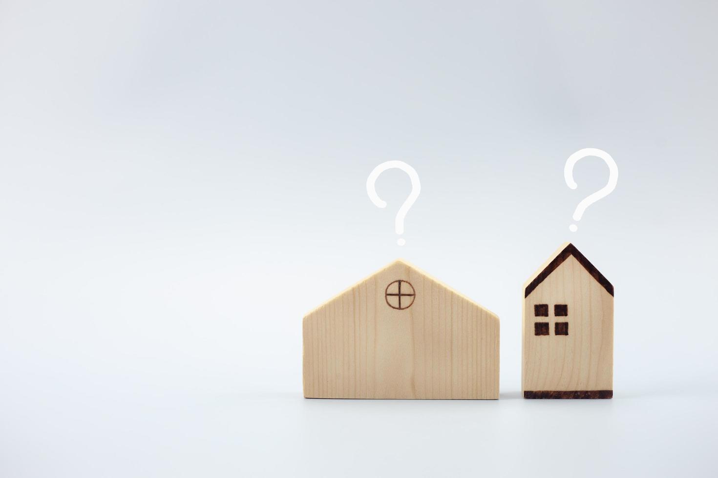 Hausmodell mit Fragezeichen auf blauem Hintergrund, Planung des Immobilienkaufs foto