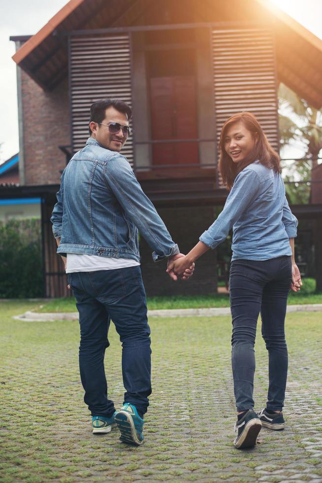 Nahaufnahme eines liebevollen Paares, das beim Gehen im Freien Händchen hält, zurückblickt und in die Kamera lächelt, Konzept eines verliebten Paares. foto