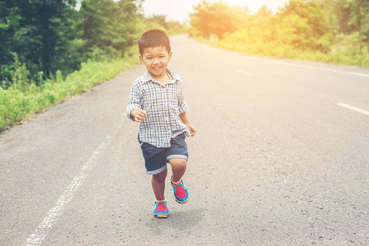 glücklicher kleiner junge in bewegung, smiley läuft auf der straße. foto