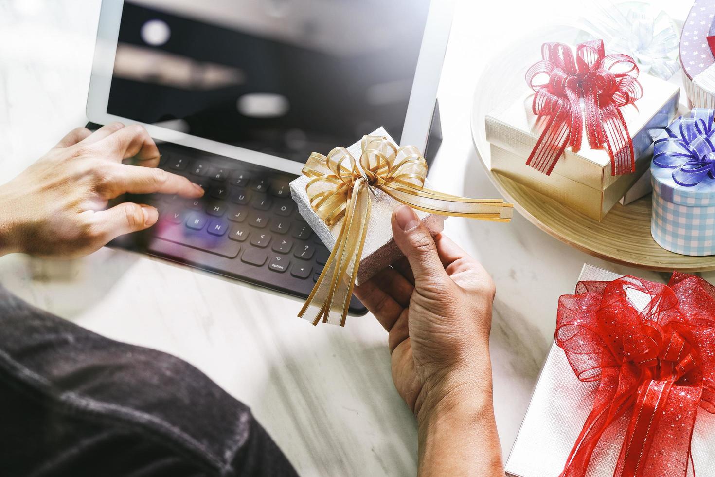 geschenk, das kreatives handschreiben und hand mit geschenk gibt. geschenklieferung, überraschung, tablet-computer, der intelligentes tastatur-smartphone auf mable-schreibtisch andockt, filterfilmeffekt foto