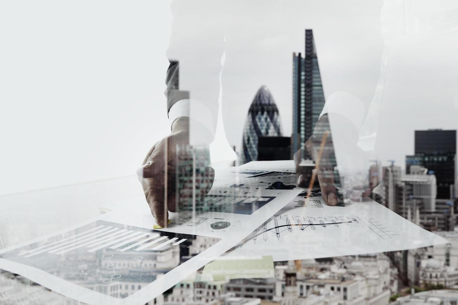 Doppelbelichtung von Geschäftsleuten, die mit neuen modernen Computern und der Londoner City arbeiten, unscharfer Hintergrund foto