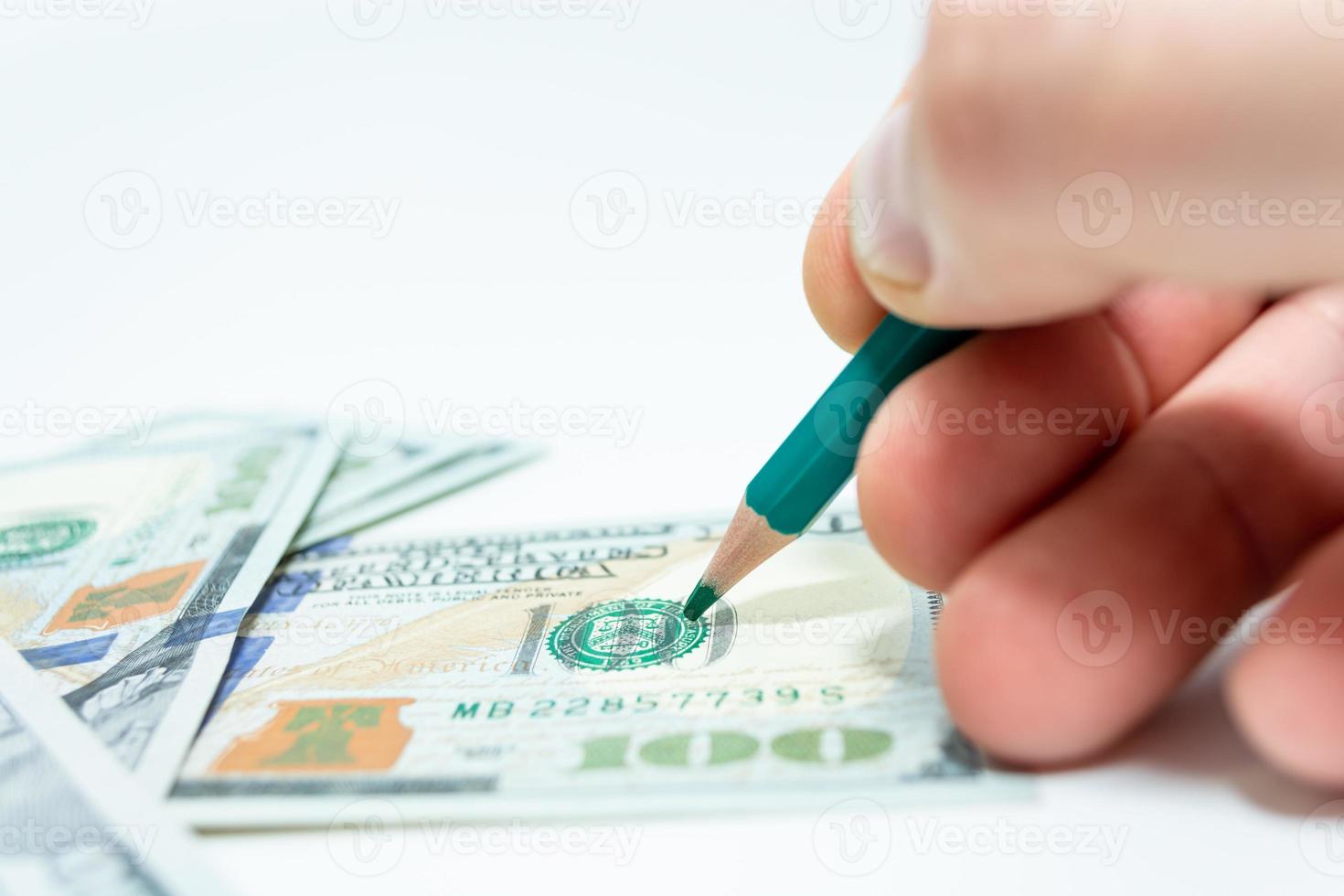 Geld abheben. Ein Knall in der Hand hält einen Bleistift über einem Hundert-Dollar-Schein. foto