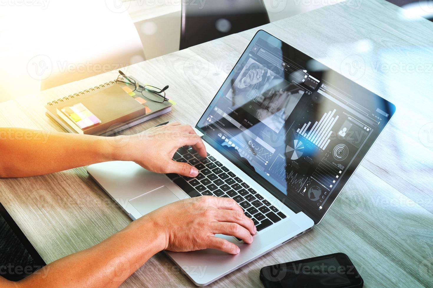 Website-Designer nimmt an einer Videokonferenz mit Laptop-Computer und Smartphone am Schreibtisch im Büro teil foto