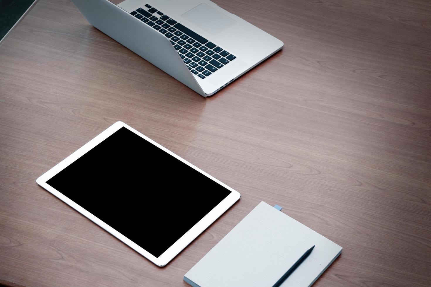 Arbeitsstation offener Laptop mit digitalem Tablet mit leerem Bildschirm auf Holzschreibtisch foto