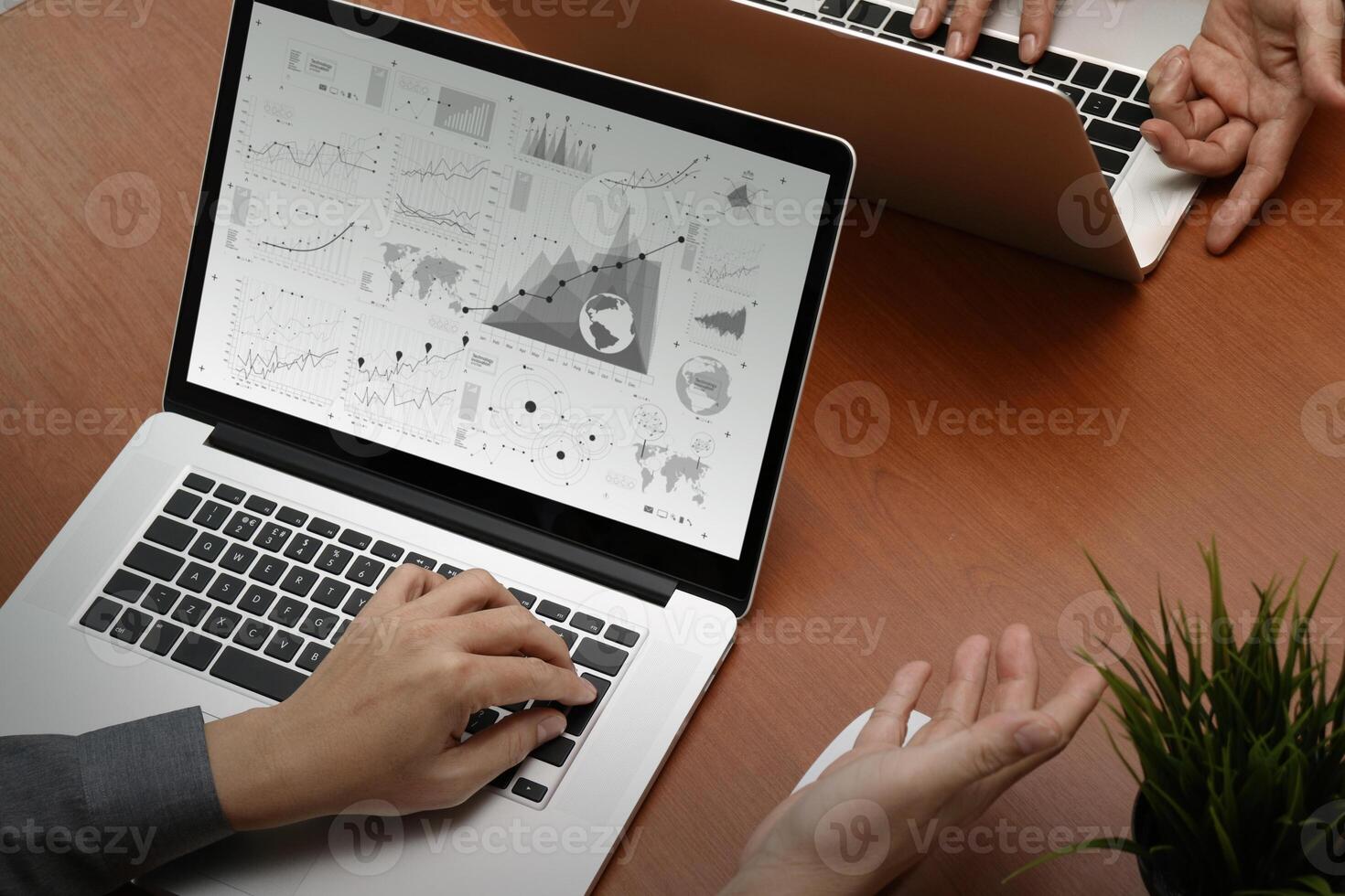 Draufsicht auf zwei Kollegen, die Daten mit einem neuen modernen Computer-Laptop mit Geschäftsstrategiedokument und digitalem Diagramm als Konzept diskutieren foto