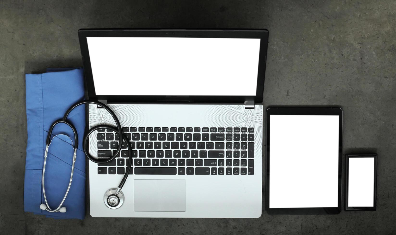Draufsicht des Arbeitsbereichs von Medizinern mit Stethoskop und blauem Mantel und Computer-Laptop mit leerem Bildschirm auf Textur-Schreibtischhintergrund foto