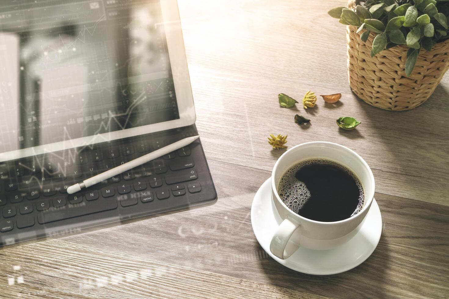 kaffeetasse und digitaler tisch docken intelligente tastatur, vasenblumenkräuter, stift auf holztisch, filtereffekt an foto