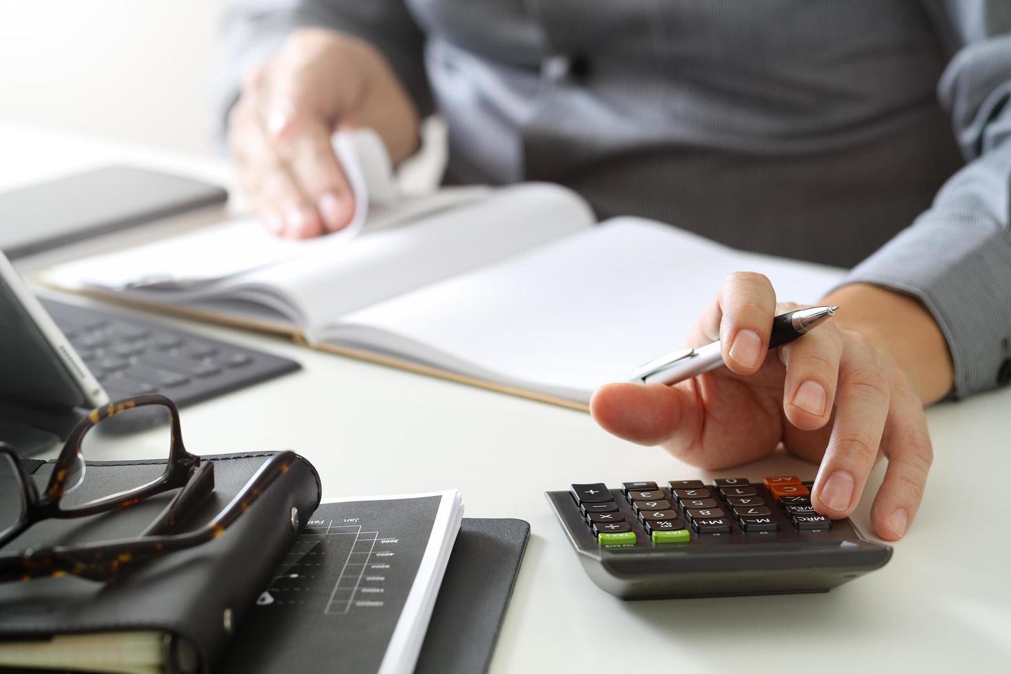 Geschäftsmann arbeitet mit Finanzen über Kosten und Taschenrechner und Laptop mit Handy auf dem Schreibtisch im modernen Büro foto