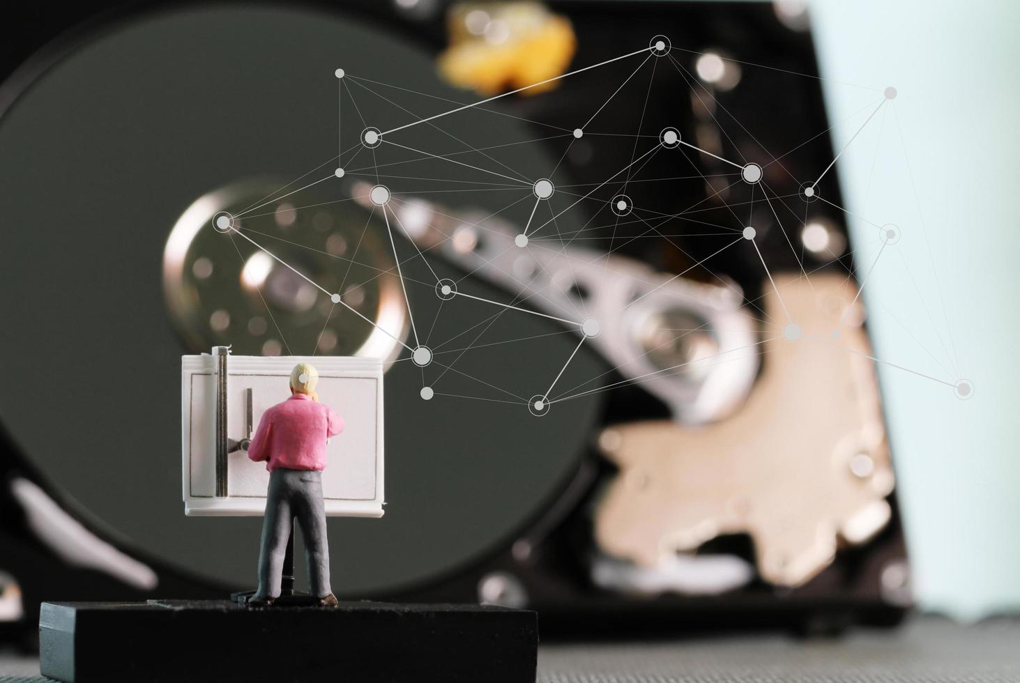 Big-Data-Konzept-Miniatur-Ingenieur, der mit Zeichentisch mit offenem Festplattenhintergrund arbeitet foto