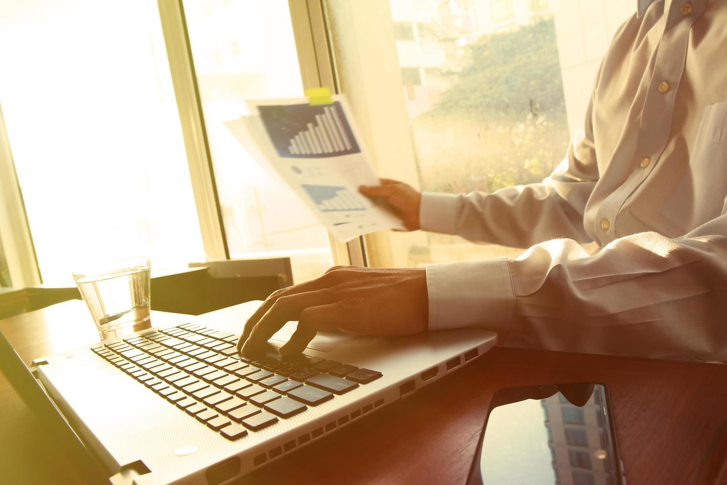 Geschäftsmannhand, die an Laptop-Computer auf hölzernem Schreibtisch als Konzept arbeitet foto