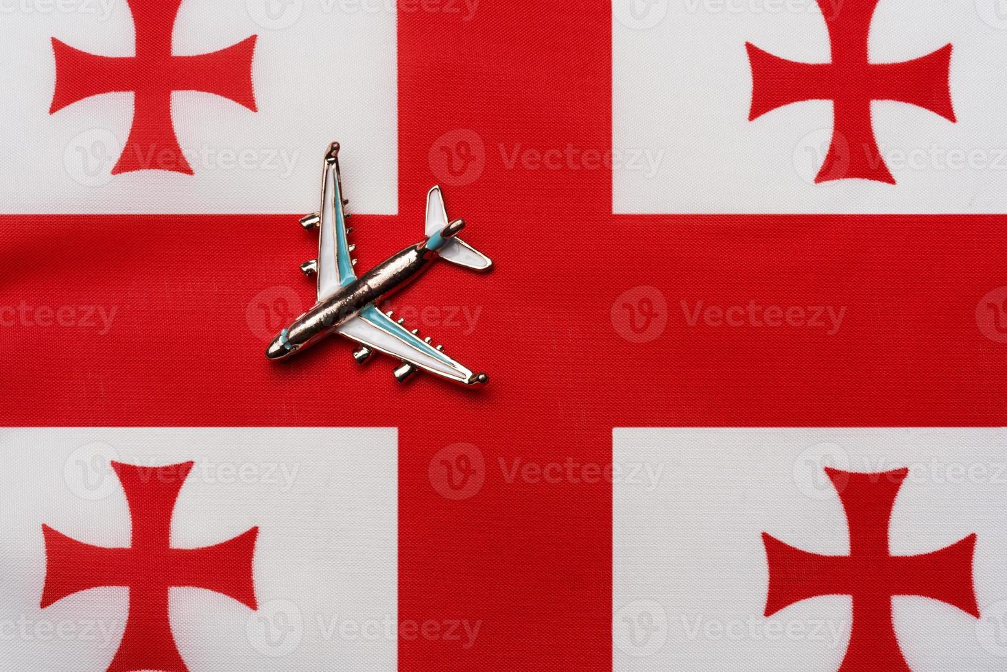 Flugzeug über der Flagge von Georgia Travel Concept. Spielzeugflugzeug auf einer Flagge. foto