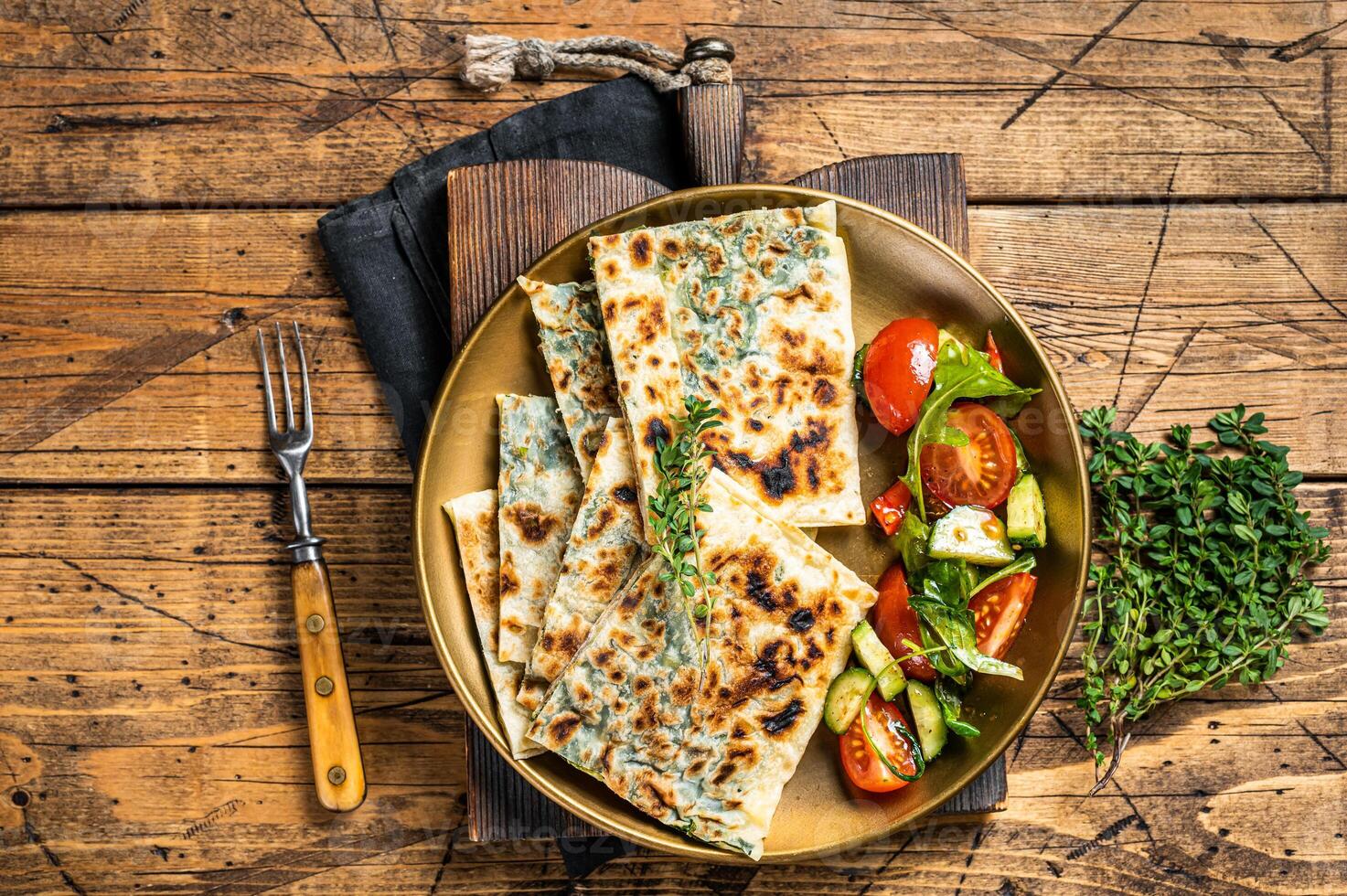 gozleme Fladenbrot mit Grüns und Gemüse Salat auf Garnierung. hölzern Hintergrund. oben Aussicht foto