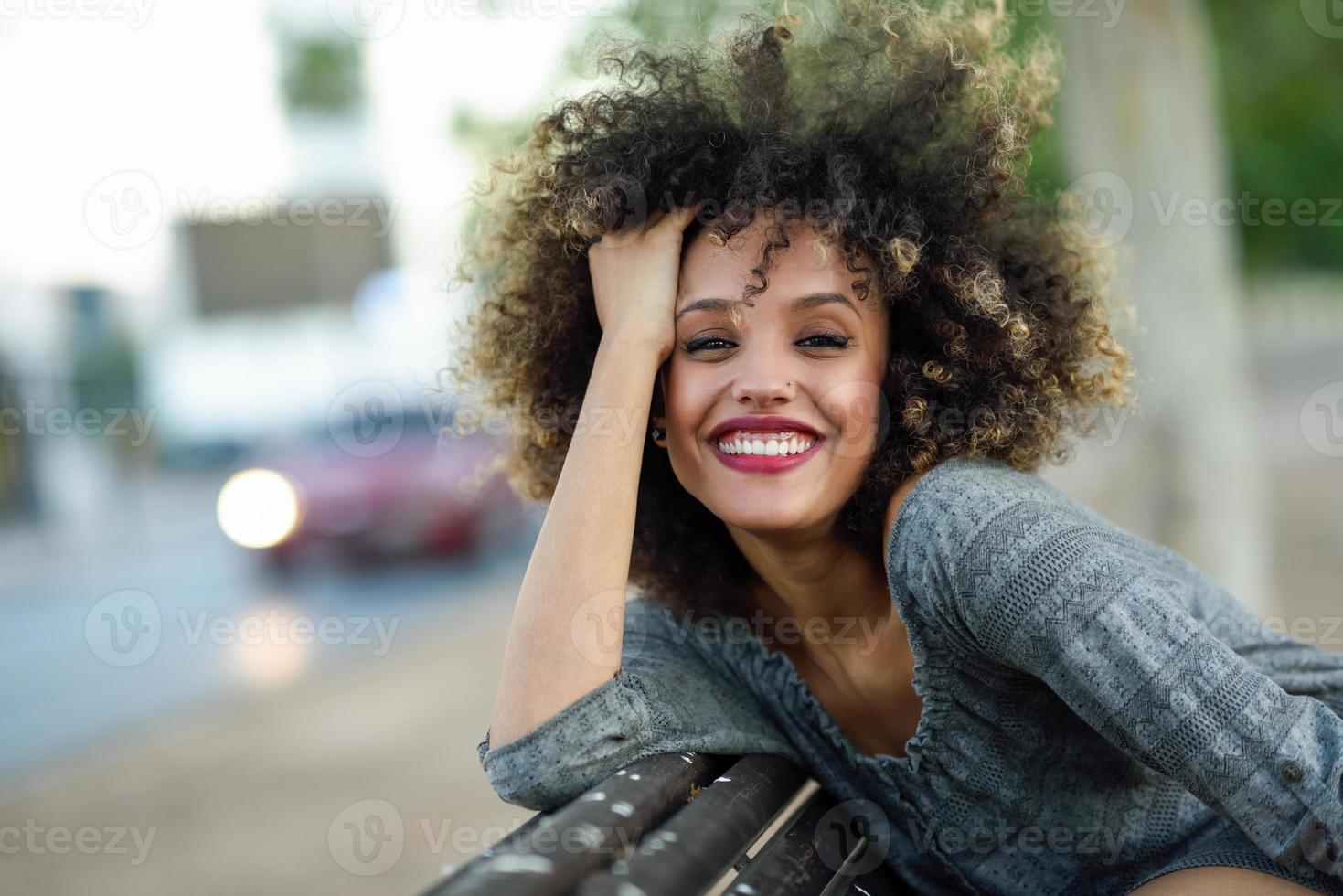 junge schwarze frau mit afrofrisur, die im städtischen hintergrund lächelt foto