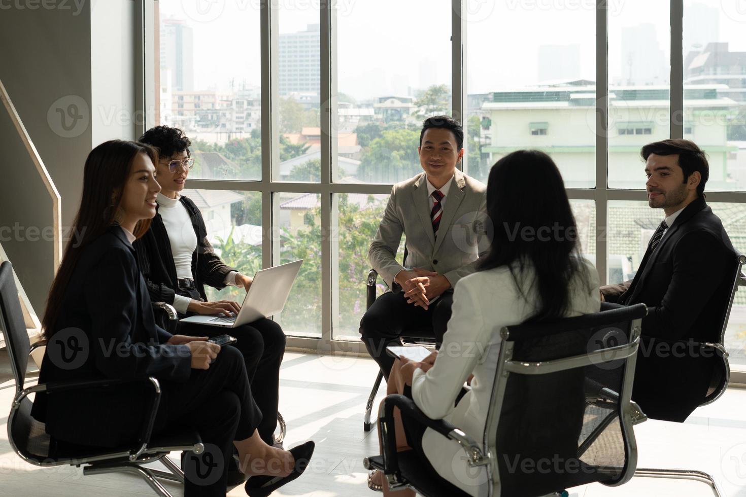 internationales geschäftsteam mit kaukasischen und asiatischen menschen, die in der nähe des fensters im büro stehen und über projekte diskutieren. Vielfalt im Geschäftskonzept foto