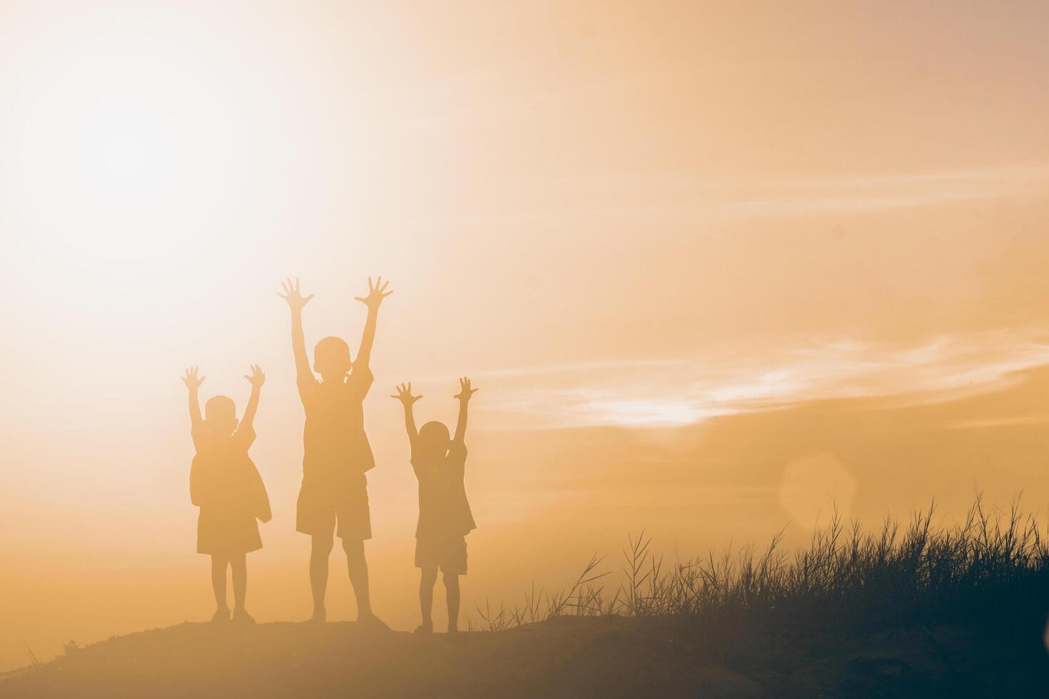 silhouette kinder, die glückliche zeit bei sonnenuntergang spielen foto