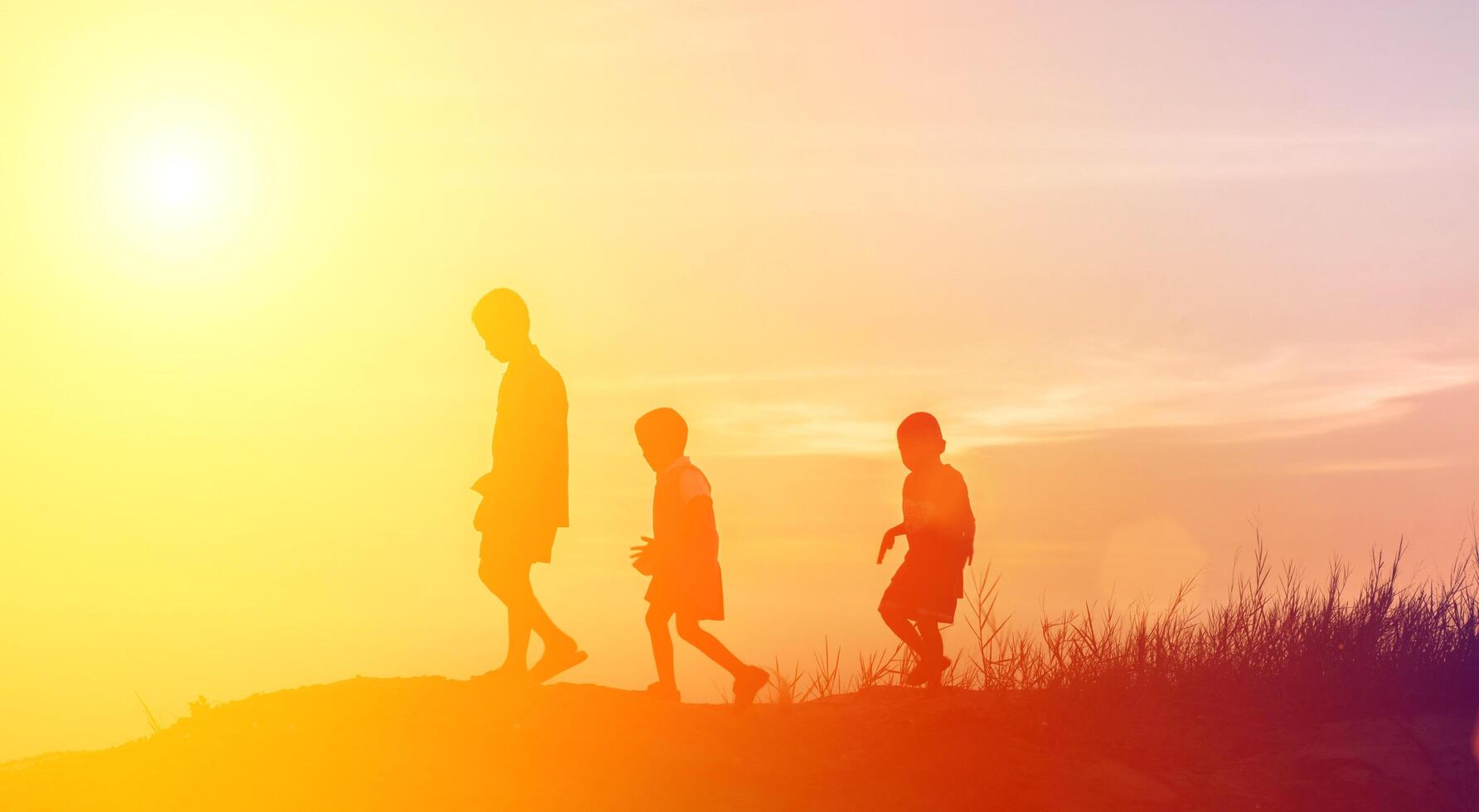 silhouette kinder, die glückliche zeit bei sonnenuntergang spielen foto