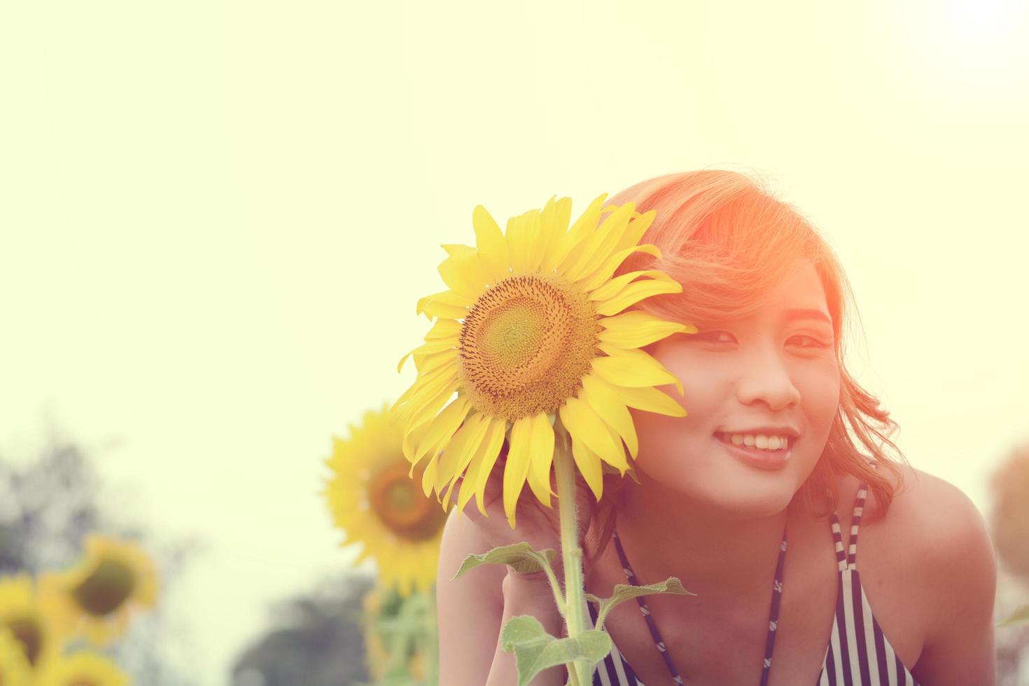 Schöne sexy Frau mit Sonnenblume in Sonnenblumenfeldern lächelt in die Kamera foto