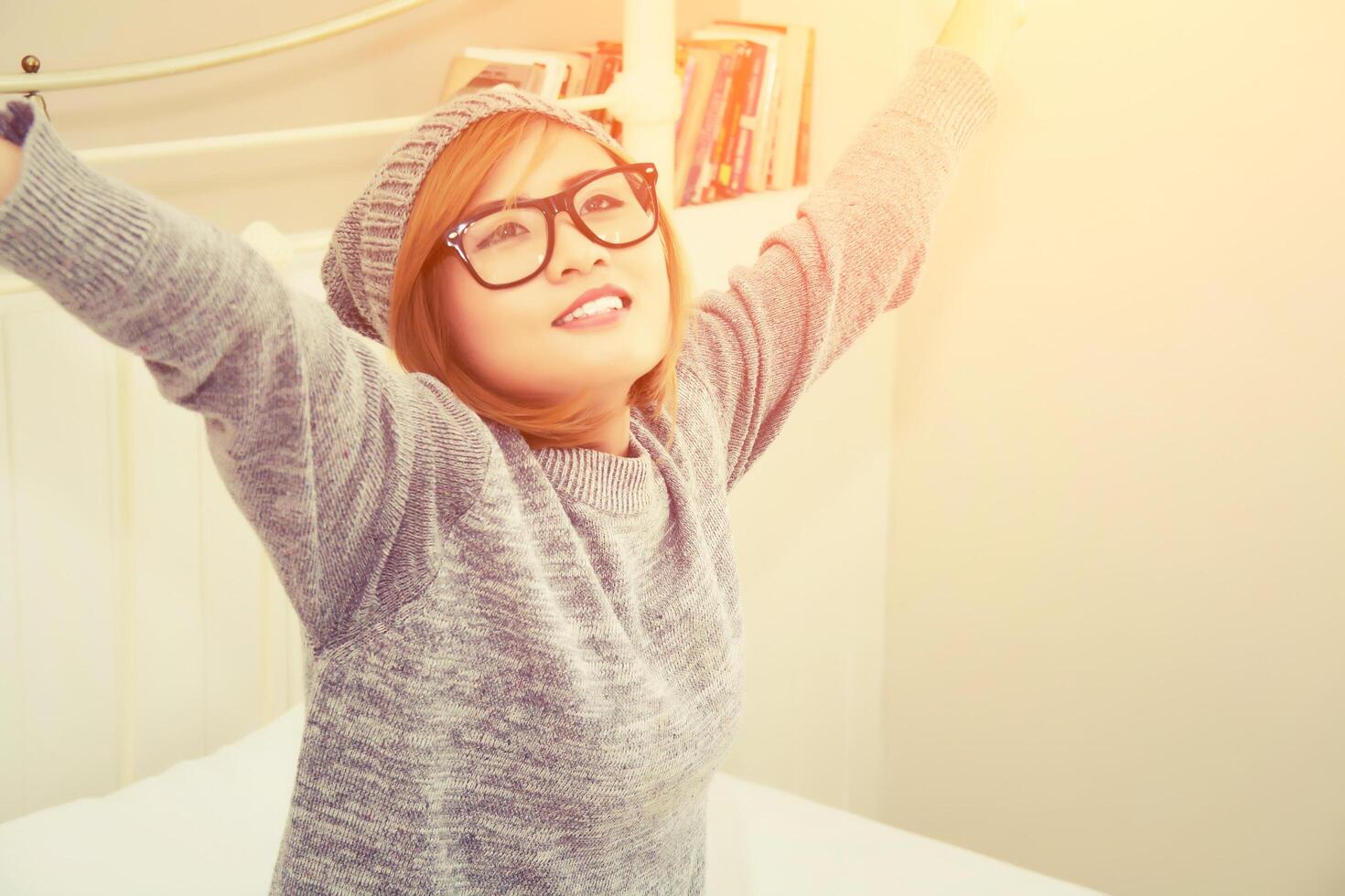 schöne junge frau, die morgens pullover auf dem bett trägt foto