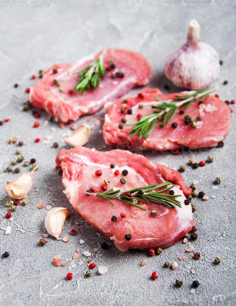 frische rohe Schweinekoteletts mit Gewürzen und Kräutern foto