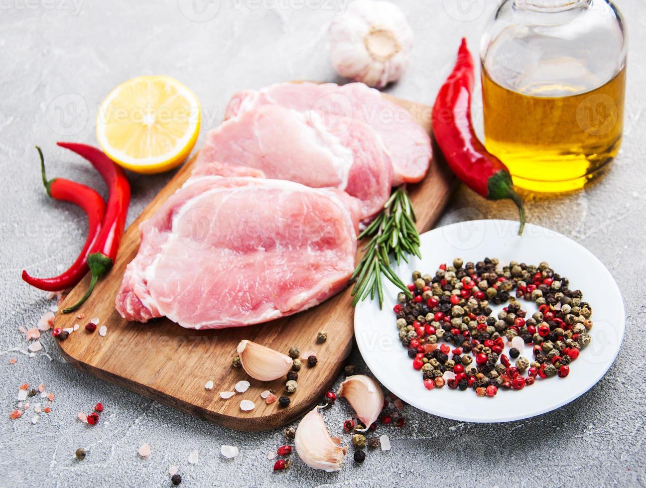 frische rohe Schweinekoteletts mit Gewürzen und Kräutern foto