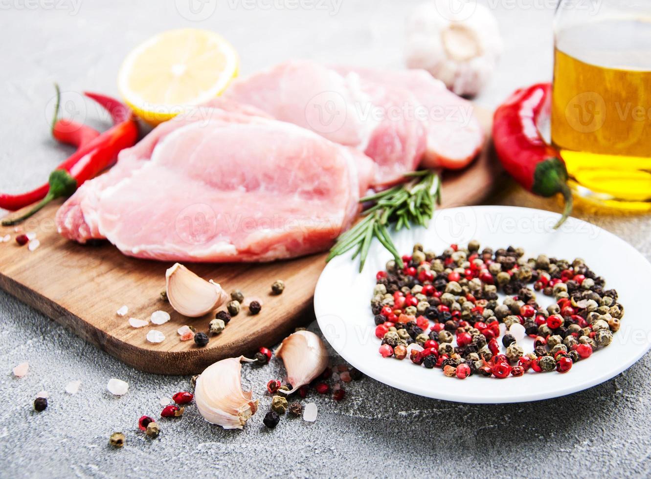 frische rohe Schweinekoteletts mit Gewürzen und Kräutern foto