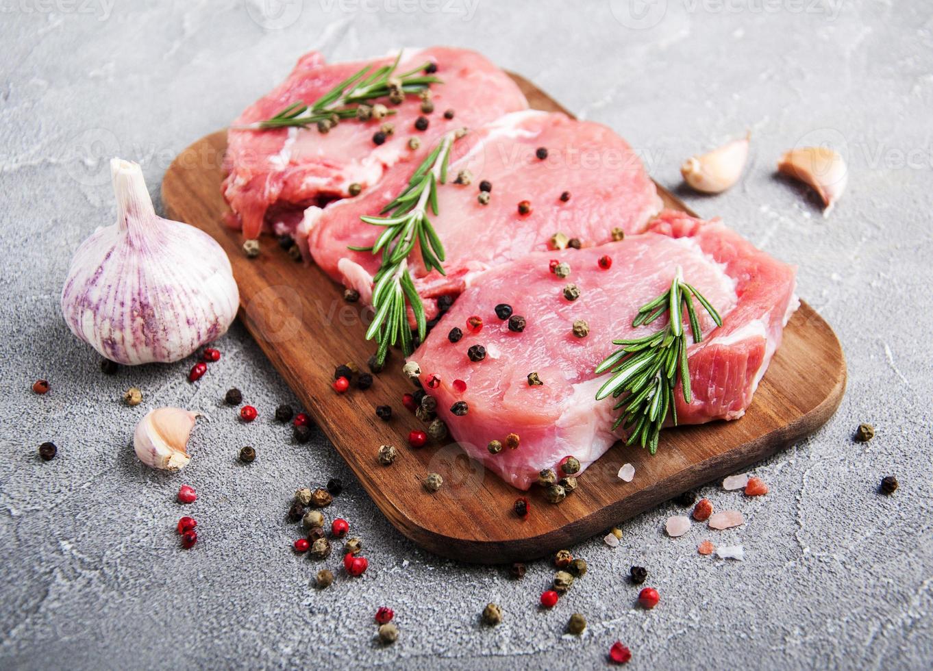 frische rohe Schweinekoteletts mit Gewürzen und Kräutern foto