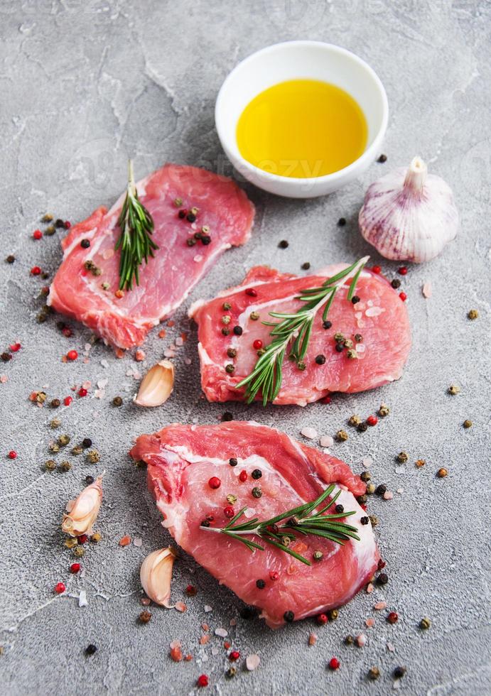 frische rohe Schweinekoteletts mit Gewürzen und Kräutern foto