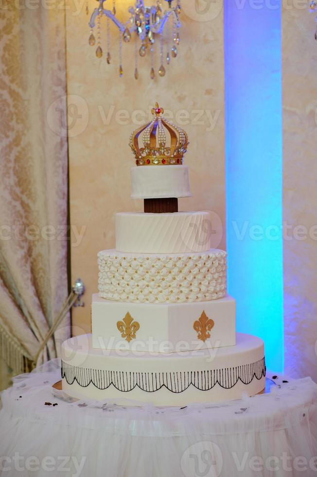 Hochzeitstorte mit Luxus in der Hochzeitsfeier dekoriert. Kuchen mit Krone verziert foto