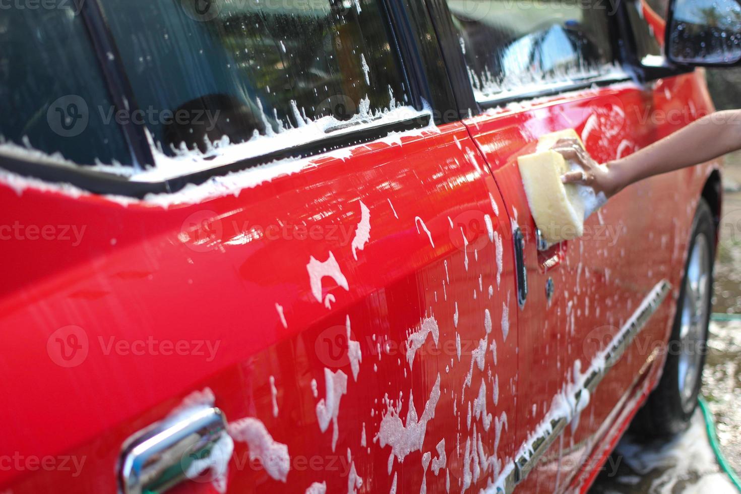 Schwamm über dem roten auto zum waschen.