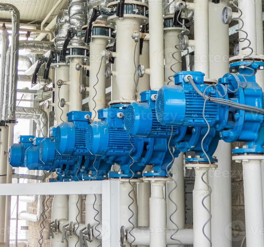 Reihe von blauen elektrischen Wasserpumpen. Rohre und Motoren in der Industrie foto