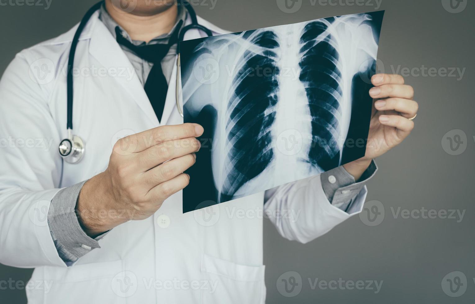 asiatischer arztmann, der röntgenfilm im laborraum hält foto