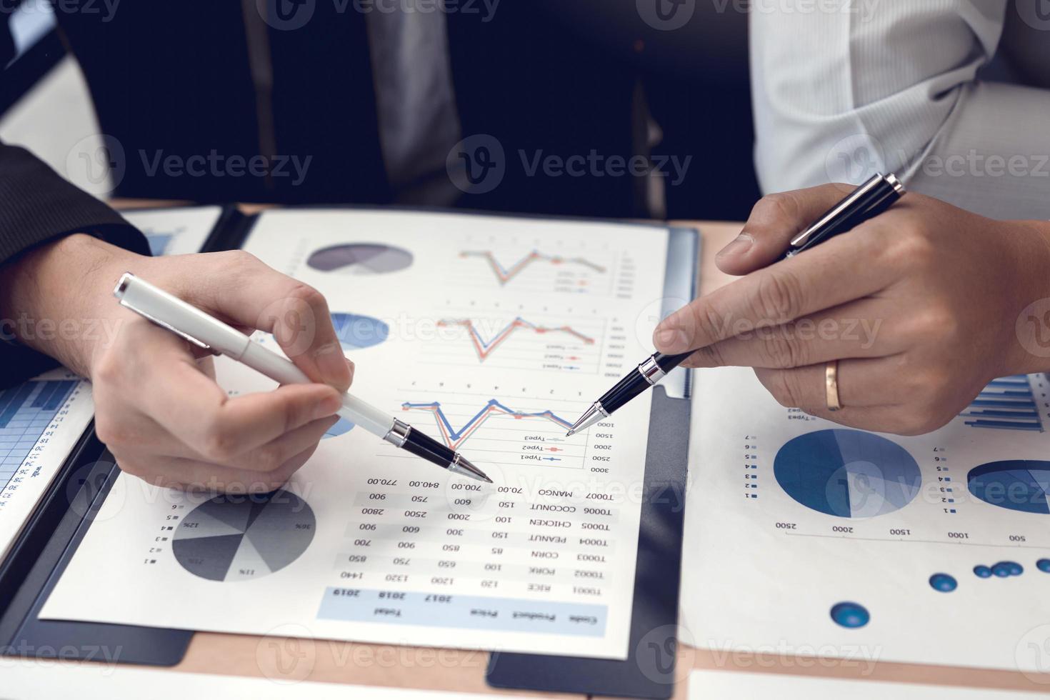 Zwei Geschäftsleute, die einen Stift halten, zeigen auf das Kostendiagramm des Unternehmens und analysieren gemeinsam die Finanzen. foto