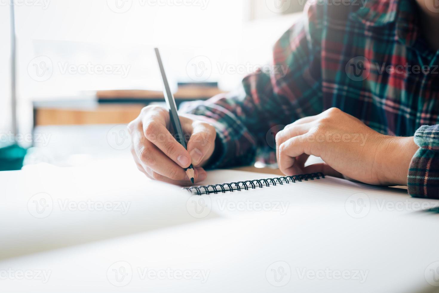 Teenager-Student arbeitet an Hausaufgaben in seinem Zimmer und schreibt in Notizbuch. foto