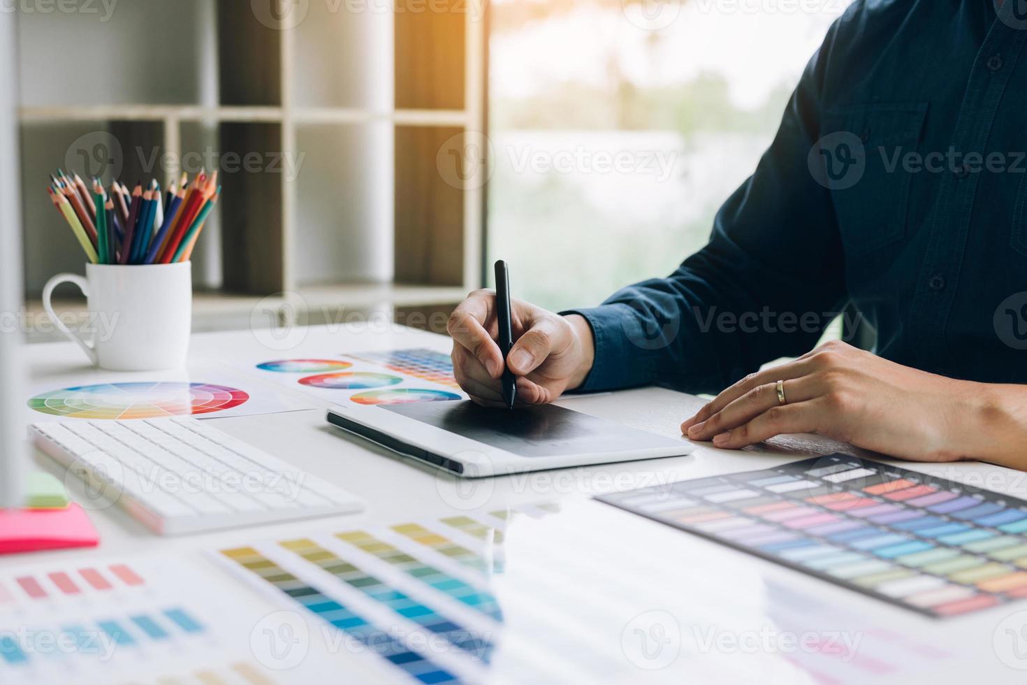 Freiberufliche kreative Designer, die mit einem digitalen Grafiktablett am Schreibtisch arbeiten und mit einem Stift im modernen Heimbüro zeichnen. foto